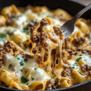 A skillet filled with cheesy tortellini and sliced beef in a creamy provolone sauce