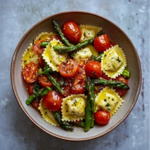 Ravioli pasta in a skillet with sautéed garlic, asparagus, and fresh cherry tomatoes