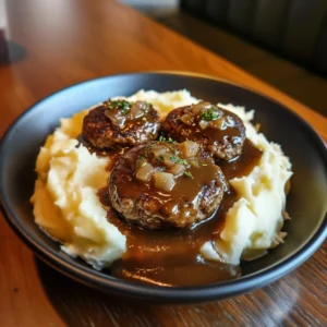 Salisbury steak covered in brown mushroom gravy next to fluffy garlic mashed potatoes