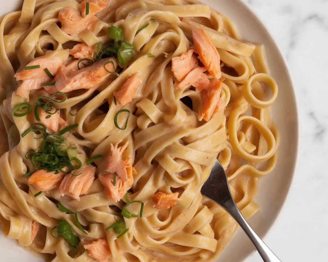 Plate of Pasta with Salmon & Creamy Garlic Parmesan Sauce, garnished with parmesan and herbs.