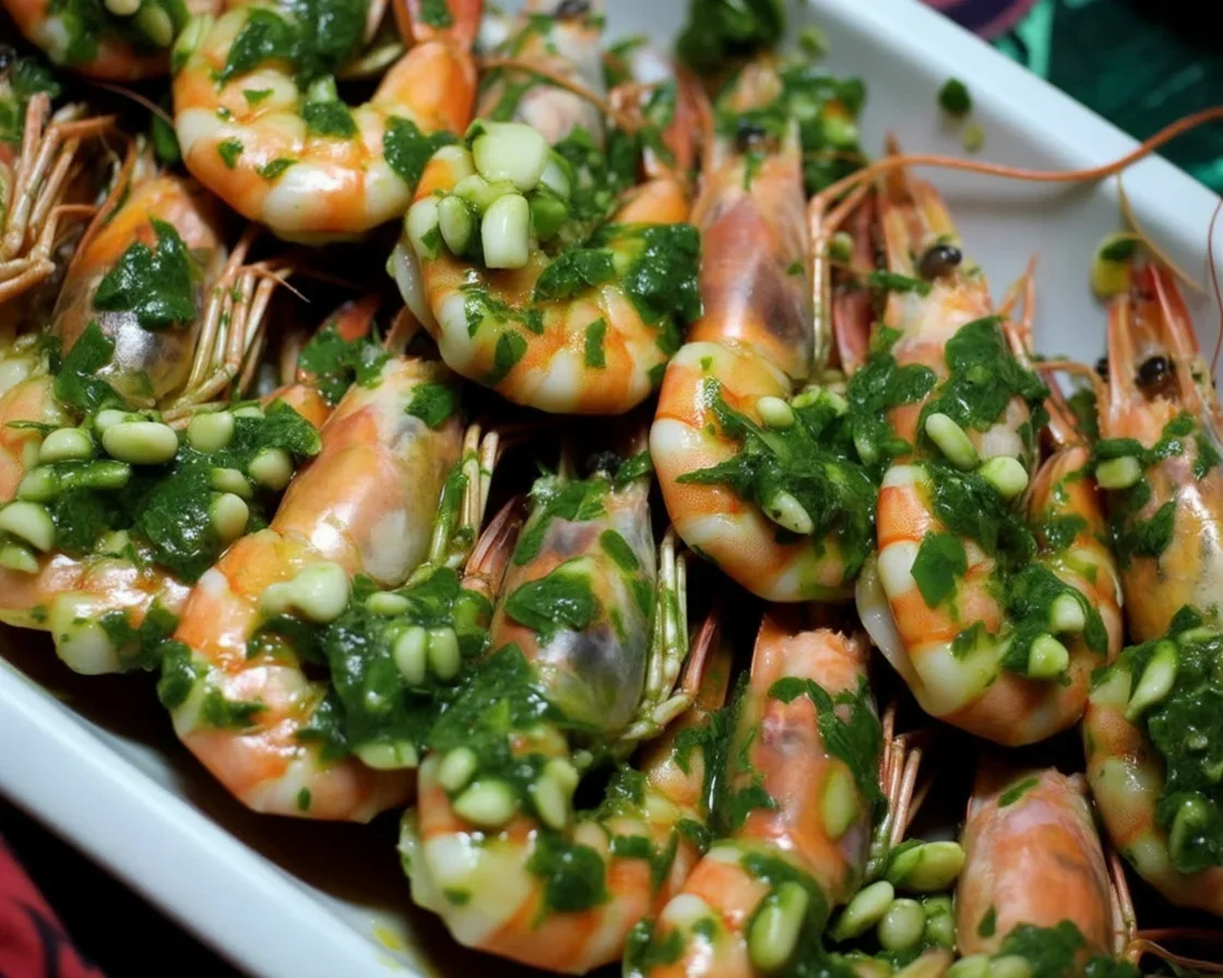 Dish of grilled prawns with garlic butter sauce and fresh parsley garnish.